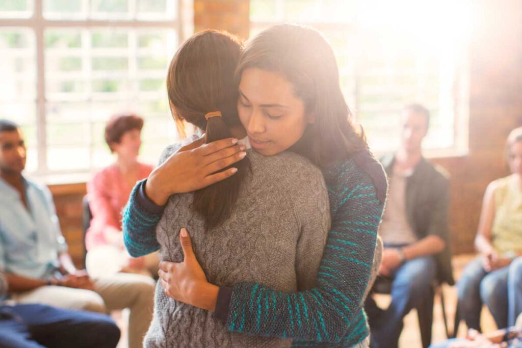 Two people embrace during opioid rehab.