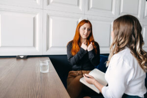 woman sitting at a table speaking to a therapist